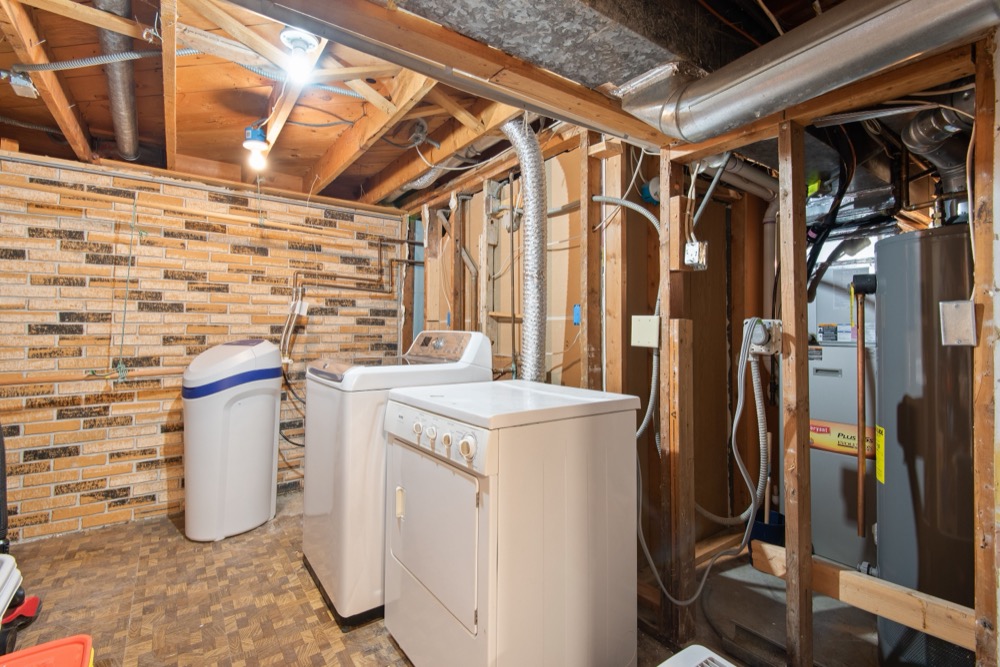 An unfinished basement with exposed joists, water heater, and block walls